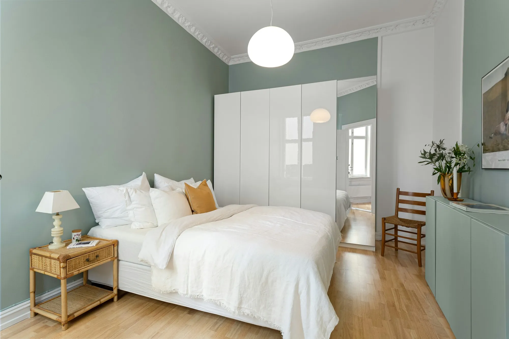 Calm bedroom with white bedding and a mint wall